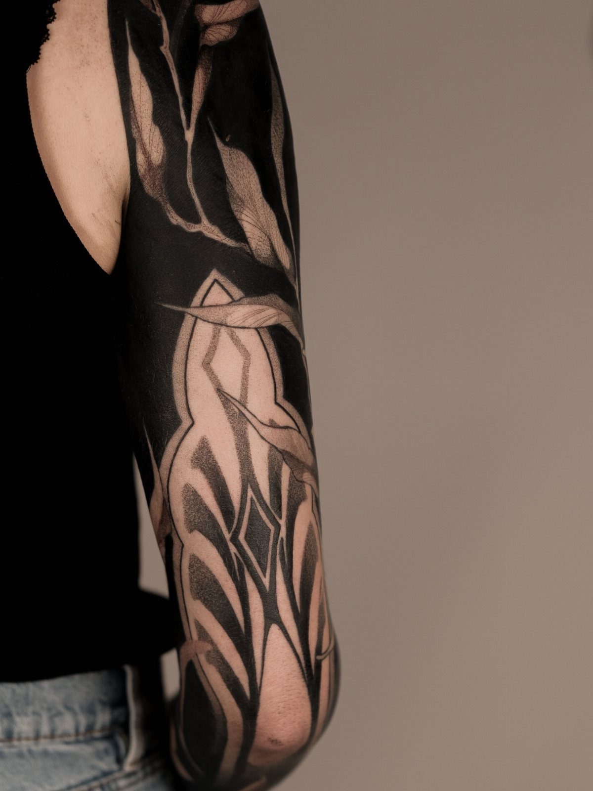 Blackout tattoo on an arm with intricate negative space organic patterns.