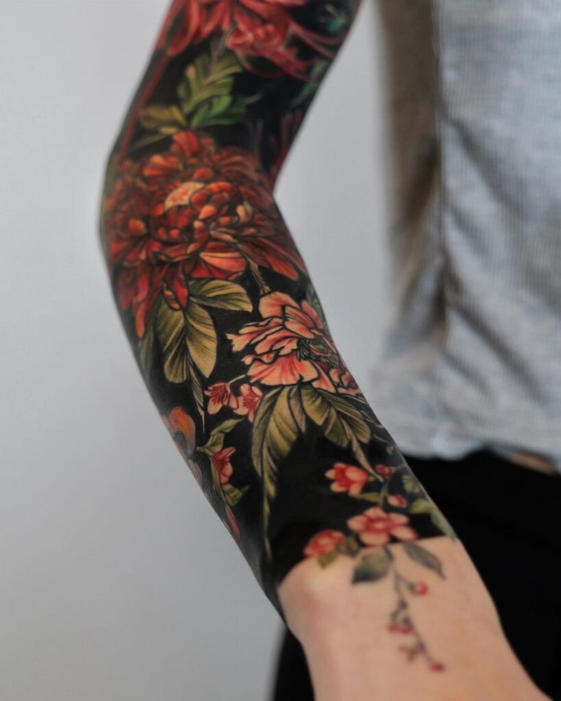 Arm sleeve tattoo with solid black background and red floral designs.