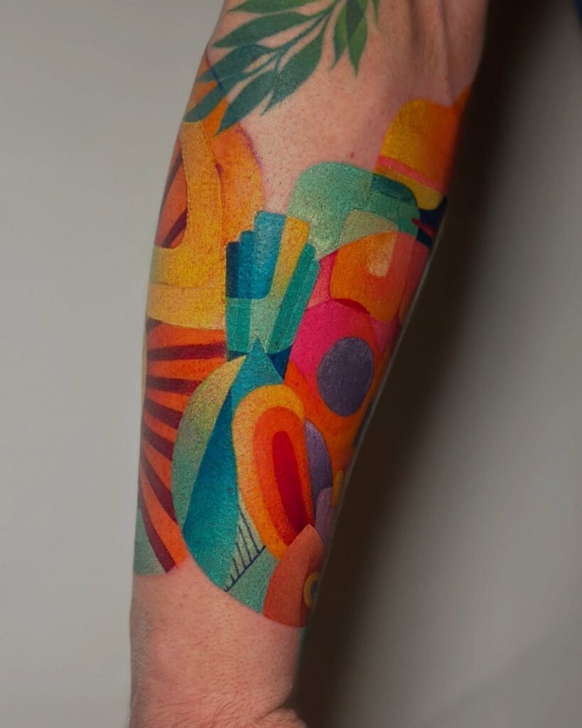 Abstract colorful tattoo on a forearm with vibrant geometric shapes and green leaves.