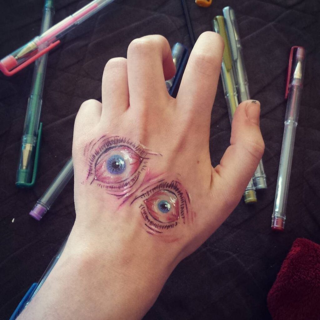 Two realistic eyes drawn with ink on the back of a hand.