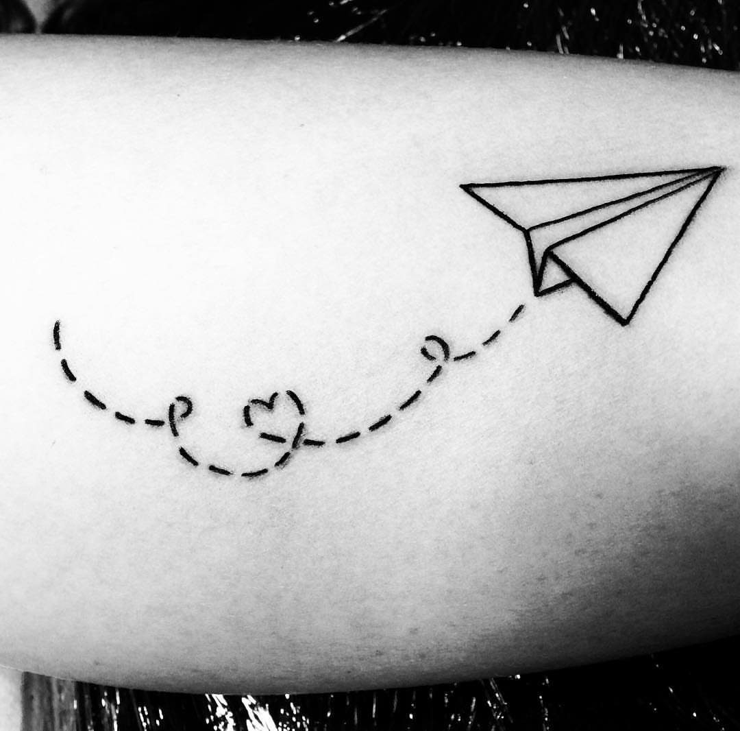 Paper airplane tattoo with a dashed line and small heart on skin