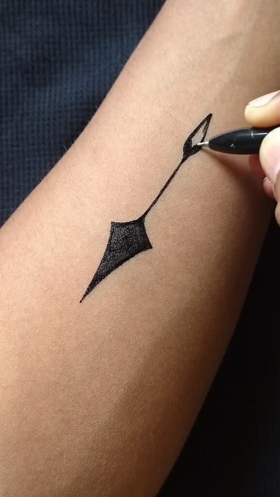 Black marker pen drawing a geometric tattoo design on a person's forearm.