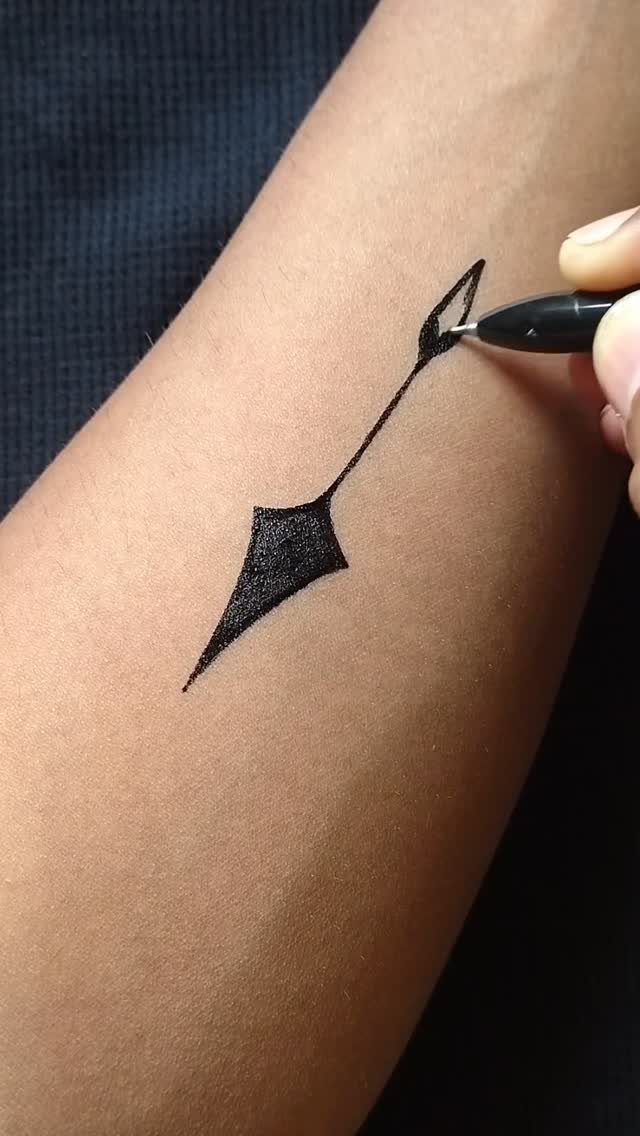 Black marker pen drawing a geometric tattoo design on a person's forearm.