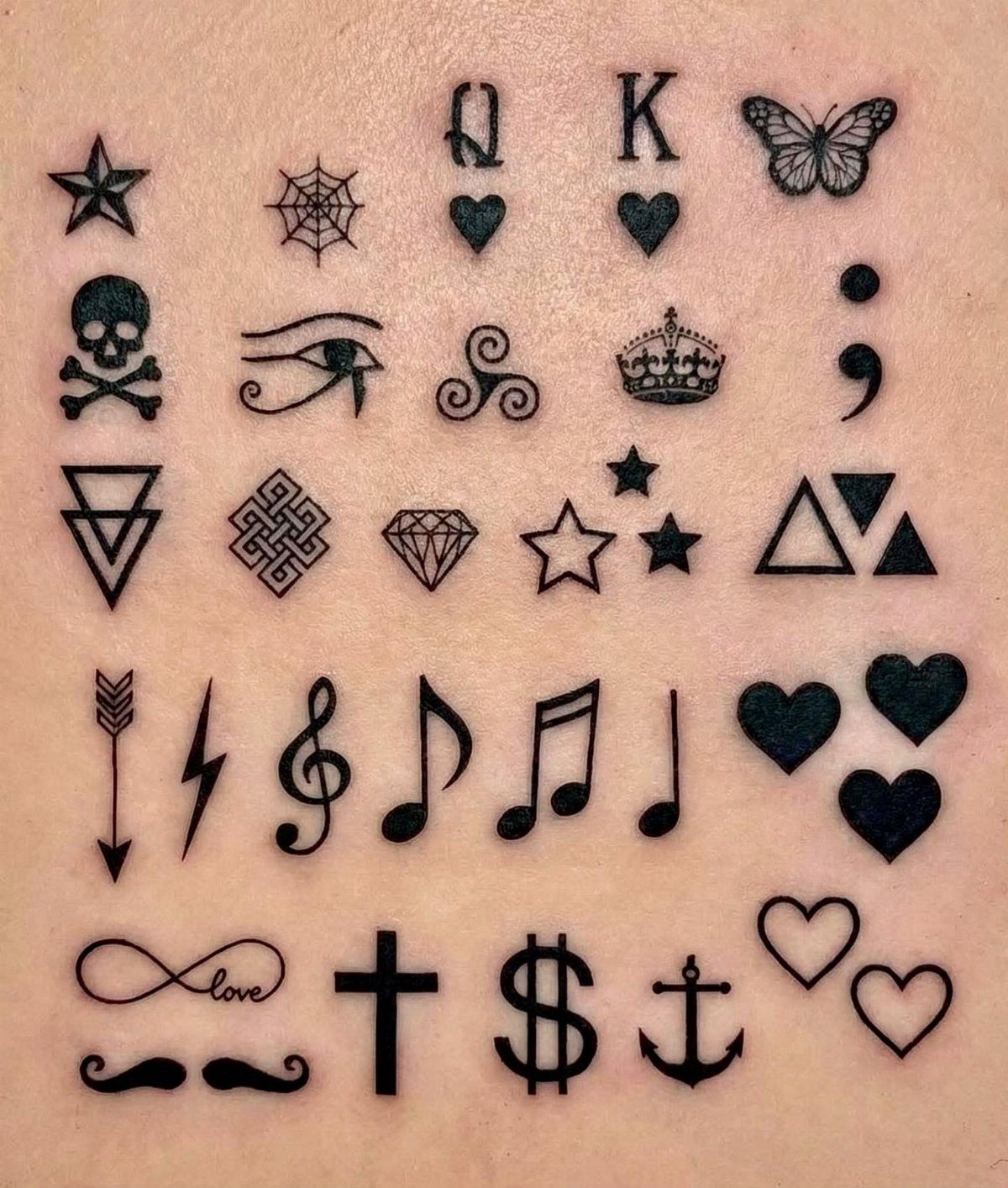 Various small black line art tattoos including symbols and musical notes on skin.