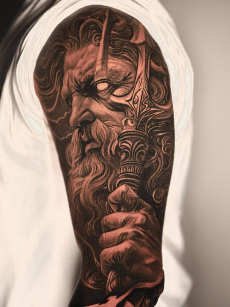 Detailed black and grey tattoo of a bearded warrior with a sword on an arm.