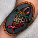 Skull tattoo with a brown hat and red bandana in traditional style.